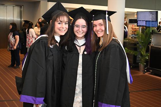 图为三名年轻的波胆网站女学生身穿毕业袍，头戴毕业帽，摆姿势拍照