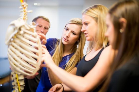 图为三名学生和一名教授在波胆网站实验室检查一具教育骨架. 