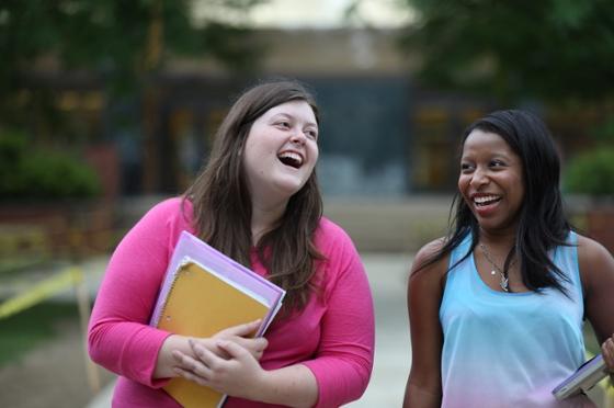 两名年轻女子在荫边校园散步，微笑着交谈
